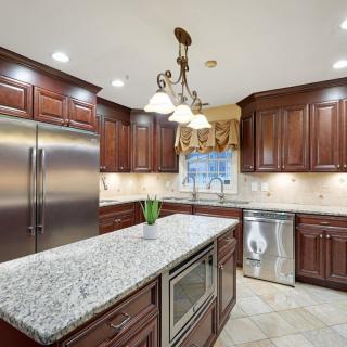 A modern kitchen with wood cabinets and granite countertops, featuring stainless steel appliances and a central island.
