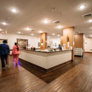 A hotel lobby with a reception desk and people walking by.