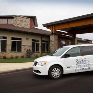 A modern facility with a branded van parked in front.