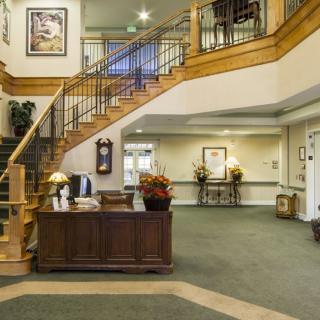 A spacious lobby area featuring a wooden staircase, reception desk, and elegant decor.
