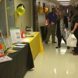 People walking past tables set up for an event in a hallway.