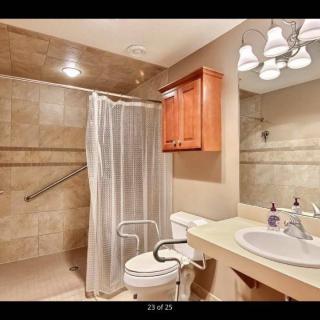 A modern bathroom with a tiled shower area, a sink, and a toilet.