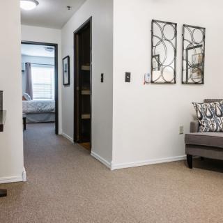 A modern living area with neutral tones features a hallway leading to a bedroom.