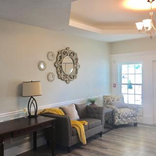 A cozy living room with modern decor, featuring a sofa, lamp, decorative mirror, and large window.