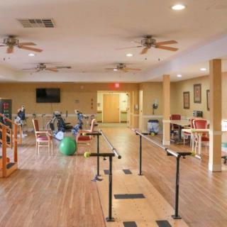 A spacious rehabilitation and exercise room with therapy equipment and wooden flooring.