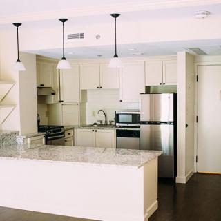 Modern kitchen interior with stainless steel appliances and pendant lighting.