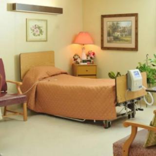 A cozy hospital room with a bed and comfortable seating.