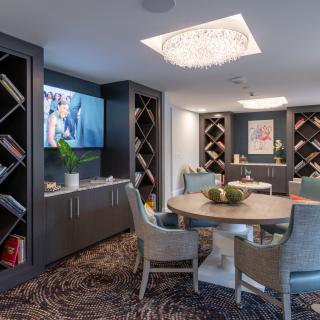A modern living area featuring elegant seating, bookshelves, and a television under a stylish chandelier.