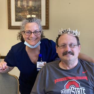 A joyful moment shared between a staff member and a resident wearing a crown in a community setting.