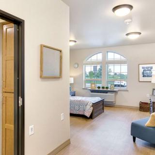 A cozy bedroom with a large window, bed, and comfortable seating area.