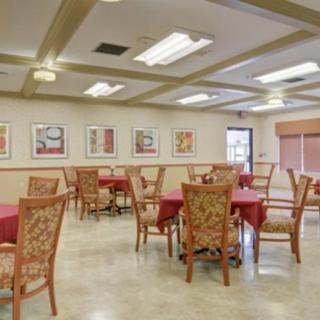 A dining area with neatly arranged tables and chairs, adorned with artwork on the walls and lit by ceiling lights.