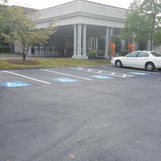 A view of a parking lot featuring designated handicap spaces in front of a building.