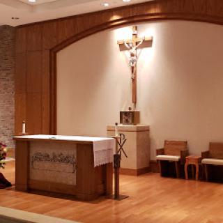 A serene view of a church altar featuring a cross, symbols of worship, and wooden elements.