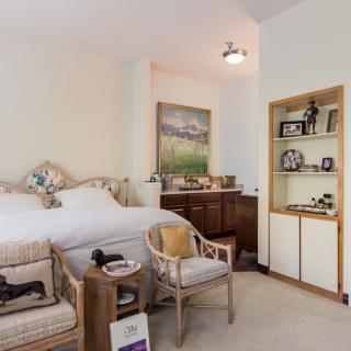 A cozy bedroom with a neatly made bed, stylish furniture, and decorative elements.