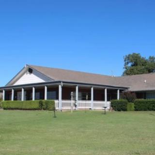 A suburban house with a large front porch and well-maintained lawn.