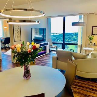 A modern living area featuring elegant decor, a large window with a city view, and a dining table adorned with fresh flowers.