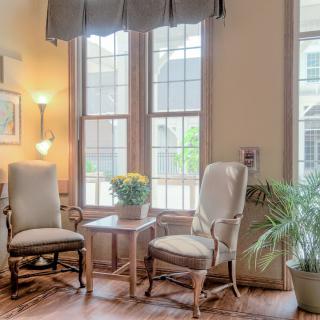 A cozy living room corner with two chairs, a small table, and plants by the window.