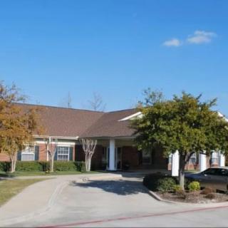 A suburban residential building with a driveway and surrounding trees.