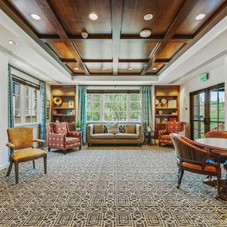 A cozy and elegant living room with comfortable seating, a patterned carpet, and large windows.