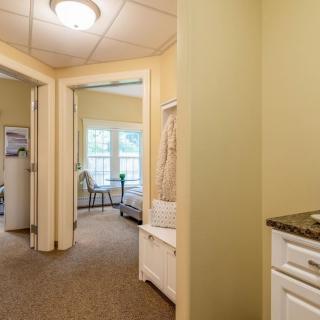 A cozy hallway leading to a bright bedroom with large windows.
