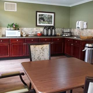 A cozy kitchenette with wooden cabinets, a table and chairs, and a coffee station.
