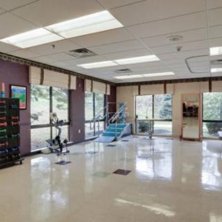 A well-lit gym with various fitness equipment and large windows.