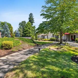 A well-maintained outdoor area with lush greenery, trees, and a paved walkway.