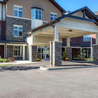 The image shows the entrance of a modern commercial building with stone accents and large windows.