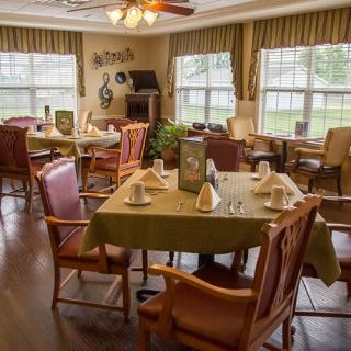 A cozy dining area with neatly arranged tables and chairs, illuminated by natural light.