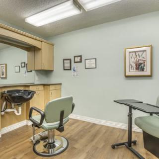 A neatly arranged hair salon interior with a styling chair and mirror.