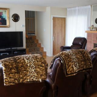 A cozy living room with leather seating, TV, and decorative blankets.