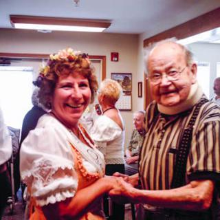 An elderly couple happily dancing together indoors.