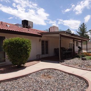 A single-story house with desert landscaping and a paved walkway.