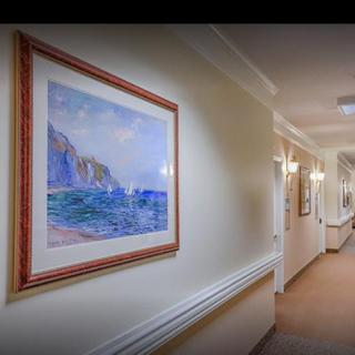 A well-lit hallway featuring framed artwork on the wall.