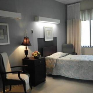 A cozy bedroom with a single bed, nightstand, and ambient lighting.