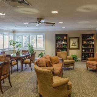 A cozy living room with comfortable seating, bookshelves, and a dining area.