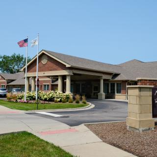 A hospital building with an entrance and flags on a clear day.