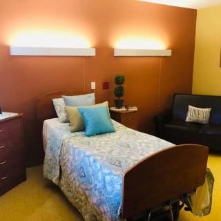A cozy bedroom featuring a single bed with decorative pillows, modern furnishings, and warm lighting.