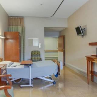 A modern hospital room with a bed, television, and seating area.