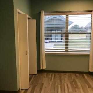 A bright and airy interior space with a window, door, and wooden flooring.