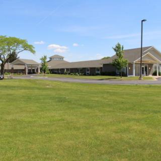 A landscape view of a building with a wide lawn and clear blue sky.
