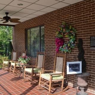 A cozy porch area featuring rocking chairs and a colorful wreath, perfect for relaxing.