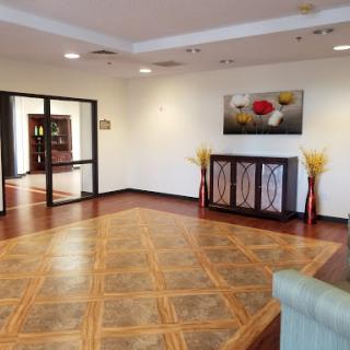 A spacious and elegantly designed lobby featuring wooden flooring, decorative furniture, and modern artwork.