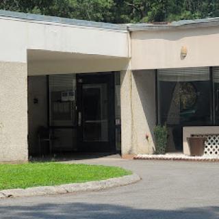 A view of the entrance to a modern building, featuring large glass doors and surrounding greenery.