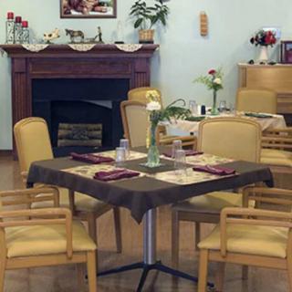 A cozy dining area with a table set for four, featuring a fireplace in the background.