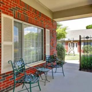 A cozy outdoor patio with metal chairs and a small table, overlooking a garden.