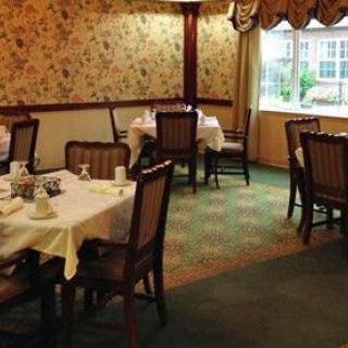 An empty restaurant dining area with classical decor and neatly arranged tables and chairs.