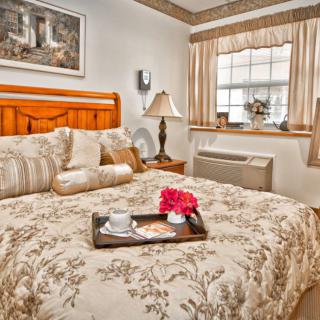A cozy bedroom with a wooden bed frame, floral bedding, and a decorative tray on the bed.