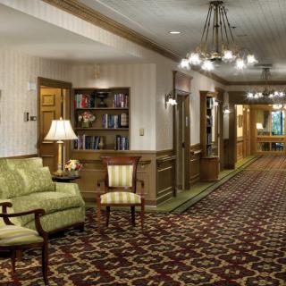 A cozy lobby area with a carpeted hallway, seating arrangements, and elegant chandeliers.