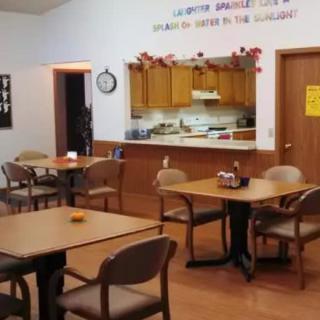 A small dining area with several tables and chairs, adjacent to a kitchen.